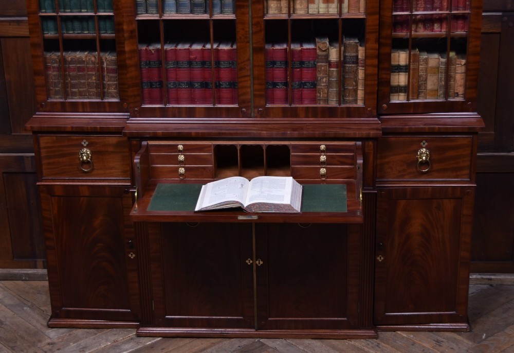 A large 19th-century flame mahogany secretaire bookcase featuring four glazed upper doors with arched astragal glazing, above a drop-down desk compartment fitted with drawers and a green writing surface. View XII