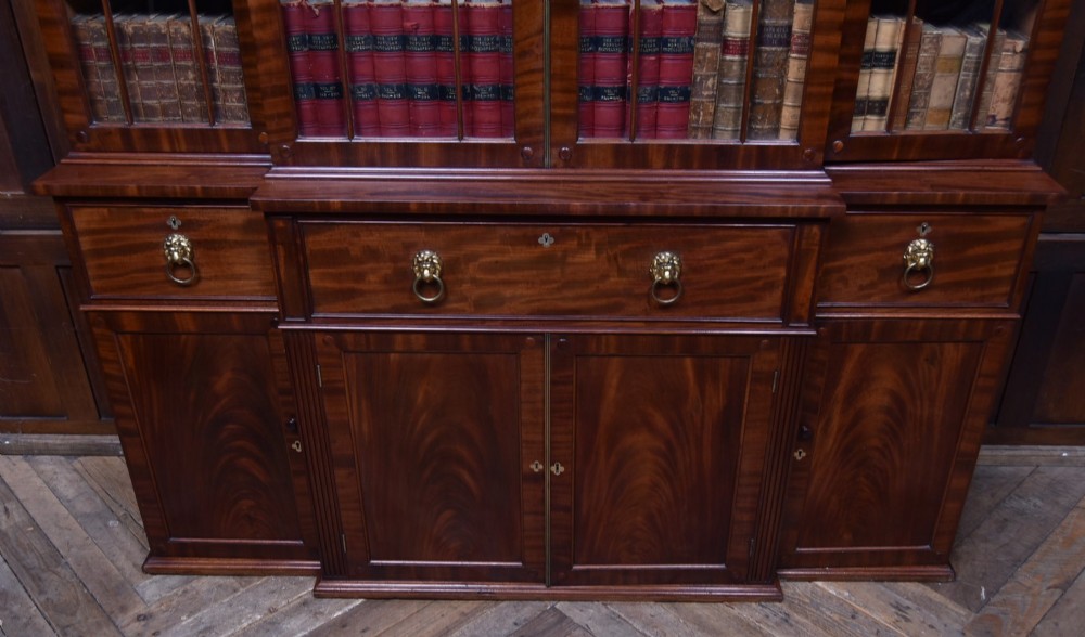 A large 19th-century flame mahogany secretaire bookcase featuring four glazed upper doors with arched astragal glazing, above a drop-down desk compartment fitted with drawers and a green writing surface. View XIII