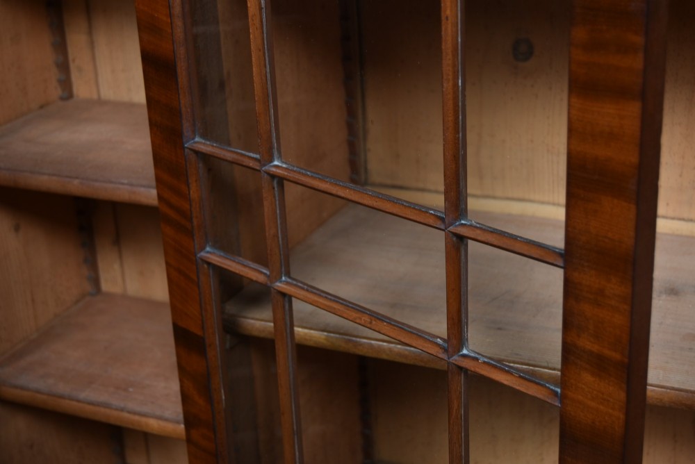 A large 19th-century flame mahogany secretaire bookcase featuring four glazed upper doors with arched astragal glazing, above a drop-down desk compartment fitted with drawers and a green writing surface. View XIV