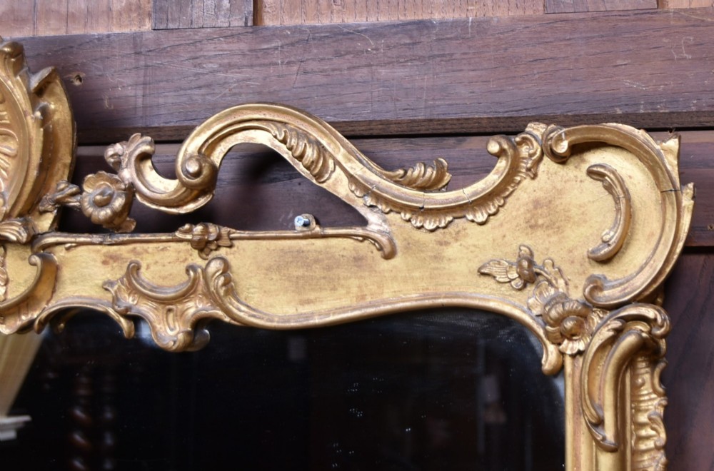 A wide Rococo style horizontal overmantel mirror with an ornate carved giltwood frame featuring an asymmetrical crest and C-scroll motifs. View II