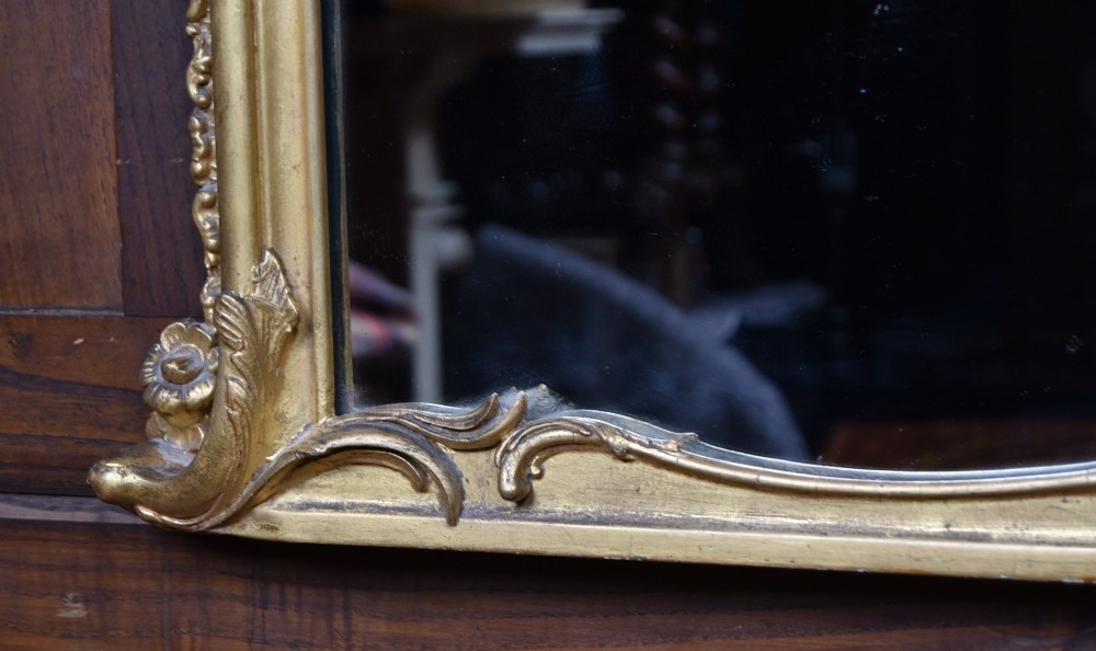 A wide Rococo style horizontal overmantel mirror with an ornate carved giltwood frame featuring an asymmetrical crest and C-scroll motifs. View V