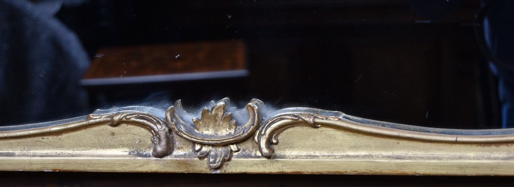 A wide Rococo style horizontal overmantel mirror with an ornate carved giltwood frame featuring an asymmetrical crest and C-scroll motifs. View VI