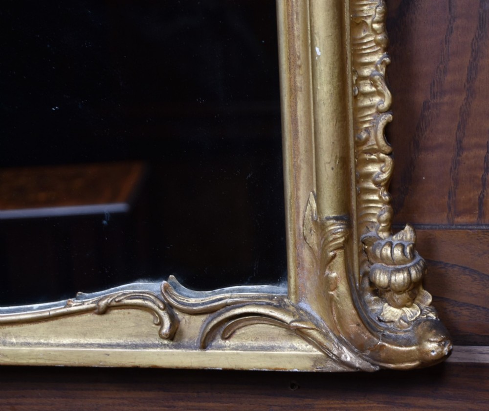 A wide Rococo style horizontal overmantel mirror with an ornate carved giltwood frame featuring an asymmetrical crest and C-scroll motifs. View VII