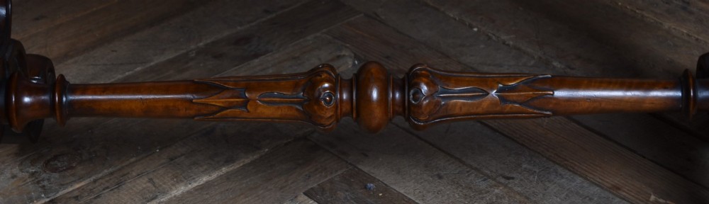 A Victorian oval centre table constructed from burr walnut, featuring carved twin pedestal legs connected by a central turned stretcher. View XII