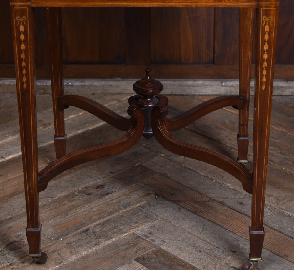 An Edwardian mahogany envelope card table featuring satinwood marquetry inlay, a single drawer, and a curved cross-stretcher with brass castors. View XV