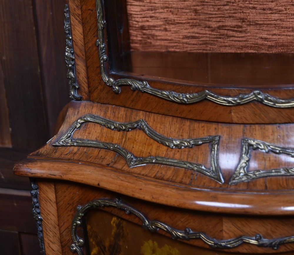 A French walnut vitrine cabinet featuring curved glass upper panels, gilt-bronze ormolu mounts, cabriole legs, and a hand-painted lower door panel depicting a figurative scene. View V
