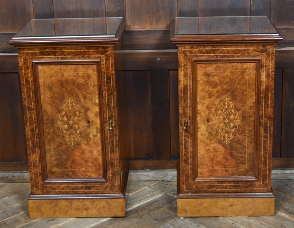 A matching pair of Edwardian burr walnut bedside pot cupboards featuring central marquetry inlays, single doors, glass tops, and plinth bases. View II