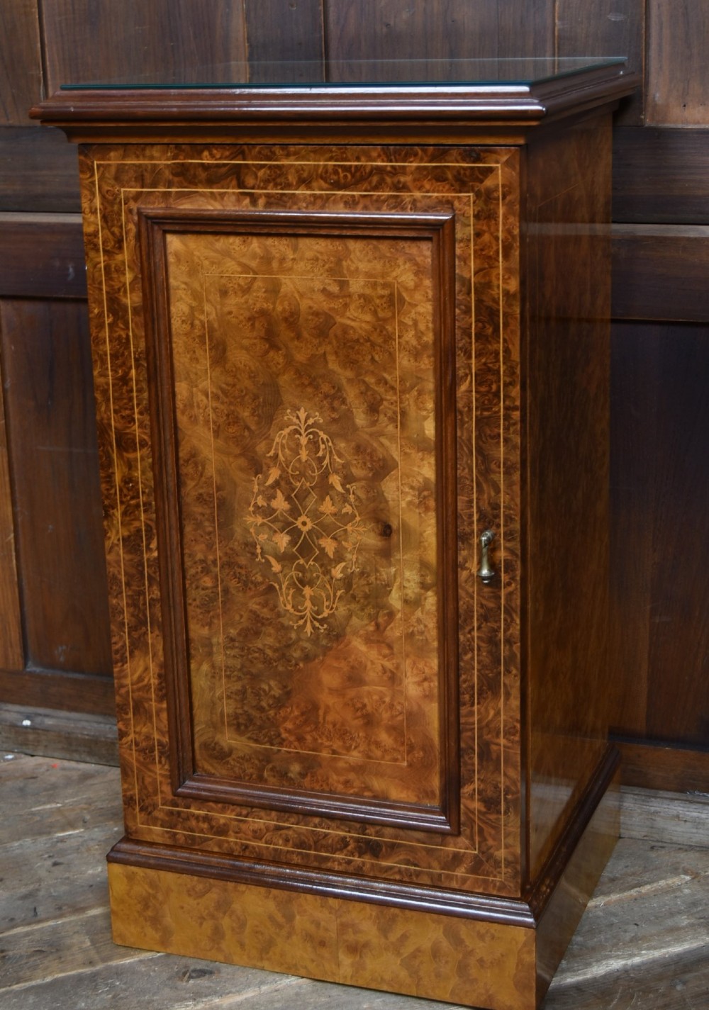 A matching pair of Edwardian burr walnut bedside pot cupboards featuring central marquetry inlays, single doors, glass tops, and plinth bases. View IV