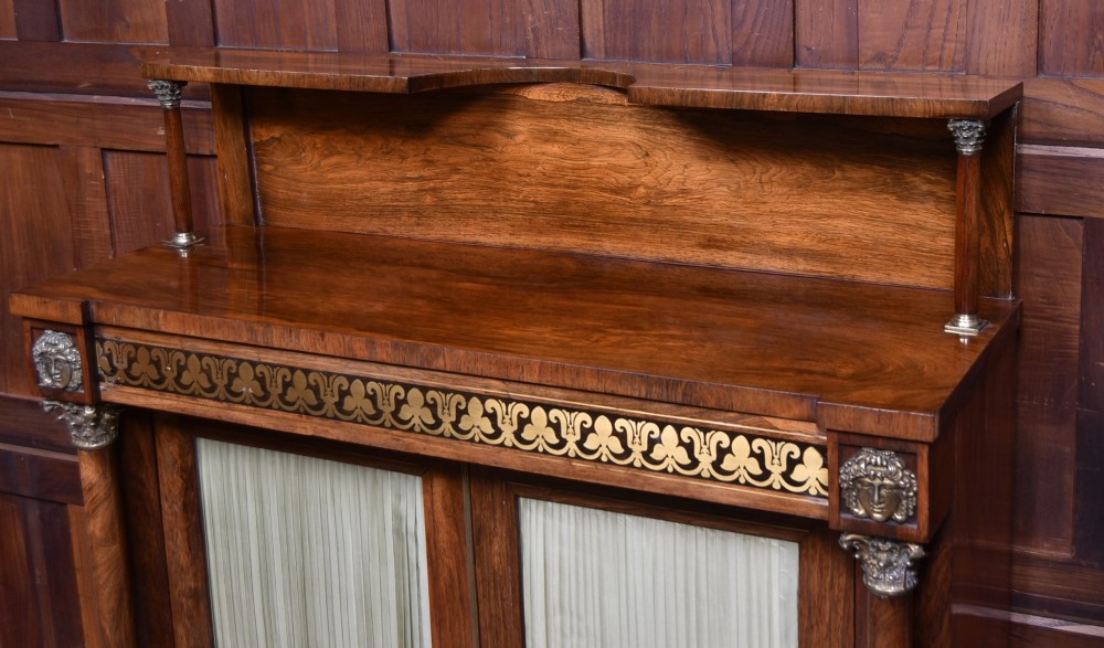 A Victorian dark rosewood chiffonier cabinet featuring a decorative brass inlay border, brass mask accents, two pleated silk fabric door panels, turned feet, and a raised upper tier shelf. View III