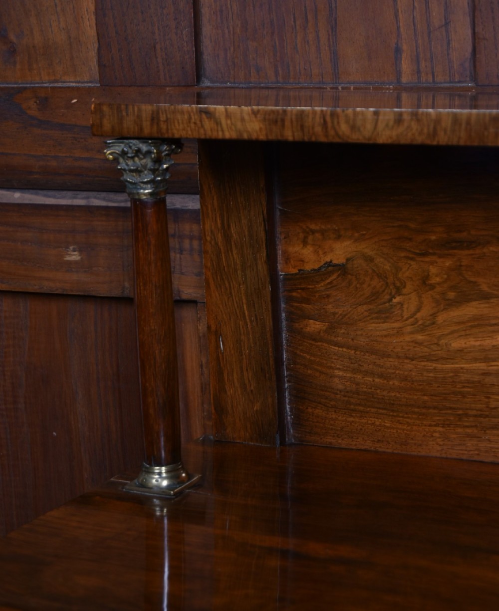 A Victorian dark rosewood chiffonier cabinet featuring a decorative brass inlay border, brass mask accents, two pleated silk fabric door panels, turned feet, and a raised upper tier shelf. View X