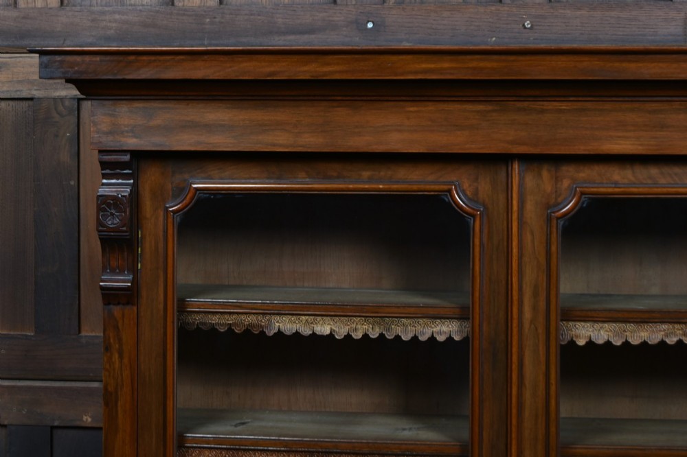 An Edwardian walnut glazed bookcase featuring a two-door upper section with glass panels, adjustable interior shelving, and a lower cabinet with burr walnut door panels. View IV