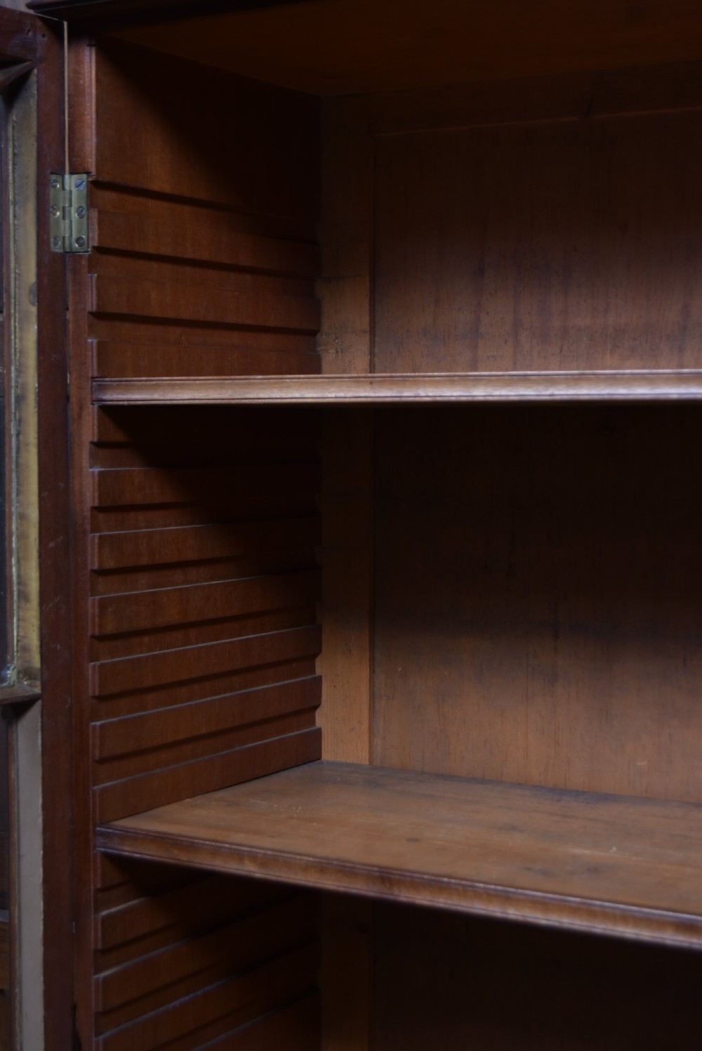 An early nineteenth-century mahogany secretaire bookcase featuring a swan-neck pediment, astragal glazed upper doors, and a lower chest of drawers with brass lion-head handles. View IV