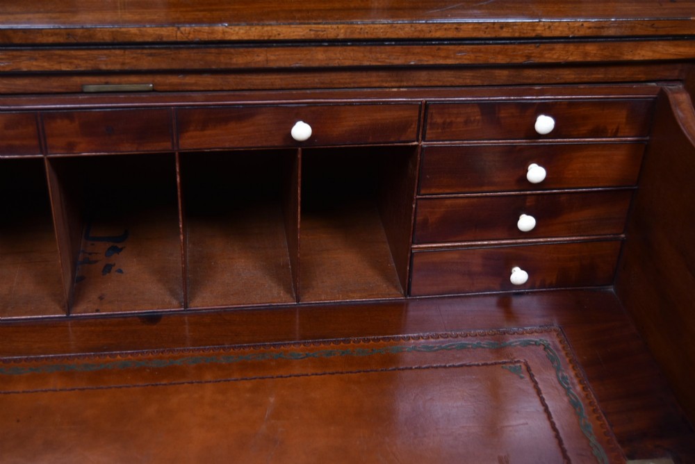 An early nineteenth-century mahogany secretaire bookcase featuring a swan-neck pediment, astragal glazed upper doors, and a lower chest of drawers with brass lion-head handles. View VII