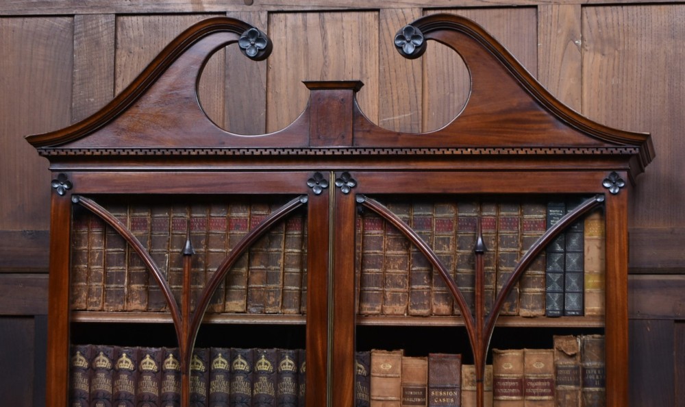 An early nineteenth-century mahogany secretaire bookcase featuring a swan-neck pediment, astragal glazed upper doors, and a lower chest of drawers with brass lion-head handles. View XIV