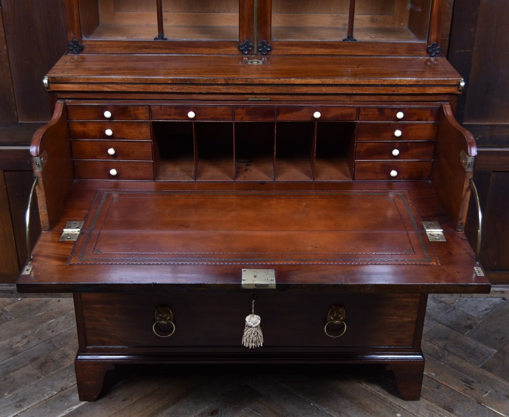 An early nineteenth-century mahogany secretaire bookcase featuring a swan-neck pediment, astragal glazed upper doors, and a lower chest of drawers with brass lion-head handles. View XV