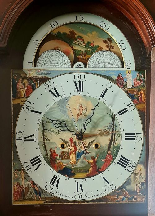 fig 2. A late 18th-century Georgian mahogany longcase clock featuring a swan-neck pediment, a painted arch dial with moon phase indicator, and a gothic shaped trunk door.