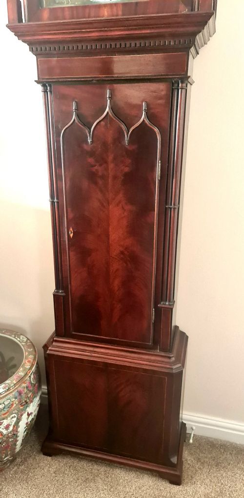 fig 3. A late 18th-century Georgian mahogany longcase clock featuring a swan-neck pediment, a painted arch dial with moon phase indicator, and a gothic shaped trunk door.