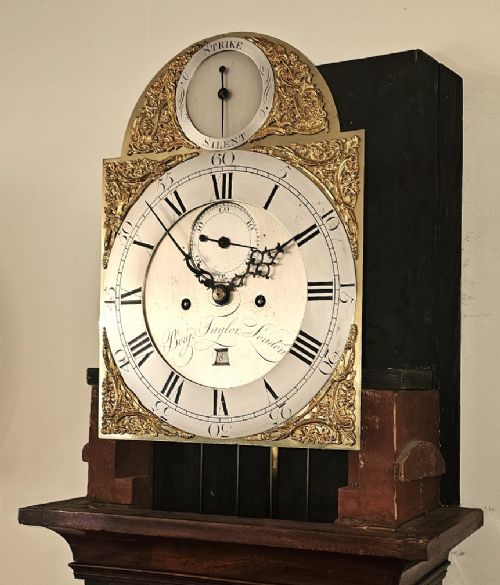 A Georgian flame mahogany longcase clock featuring an arched hood with brass-capped fluted columns, an engraved brass dial with Roman numerals, and a trunk door showcasing rich wood grain. View IX