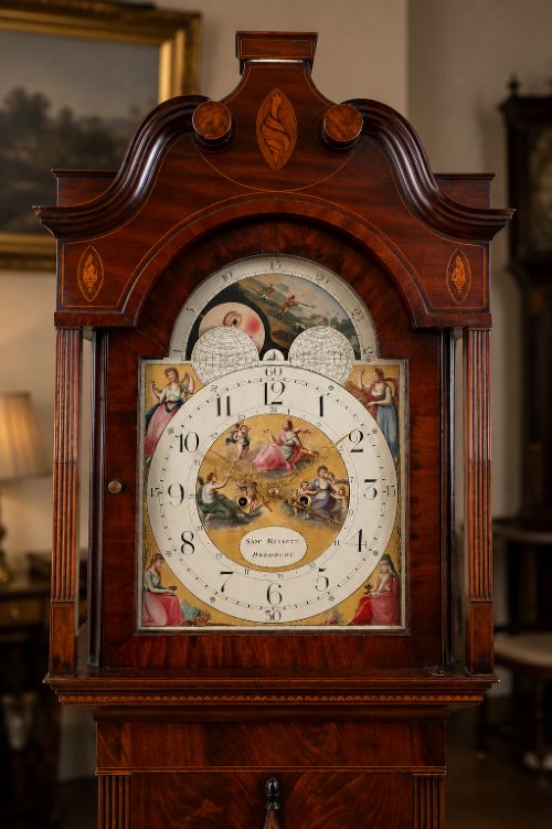 fig 1. A Regency mahogany longcase clock featuring a swan-neck pediment, a painted dial with a moonphase complication, and a Gothic arch door with flame mahogany veneers.