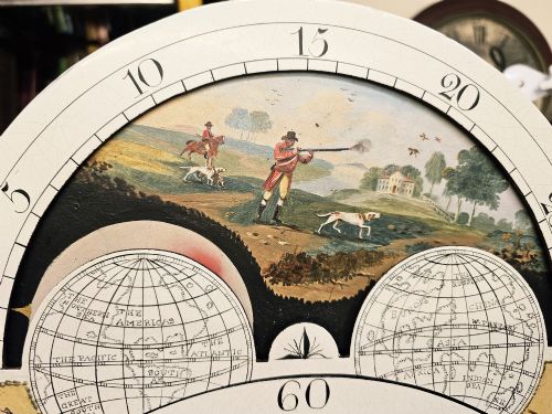 fig 3. A Regency mahogany longcase clock featuring a swan-neck pediment, a painted dial with a moonphase complication, and a Gothic arch door with flame mahogany veneers.