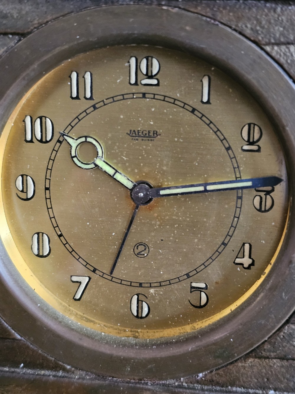 A bronzed Art Deco table clock shaped like a dog kennel with sunflowers on top and a dog figure on the left side of the circular dial. View VI