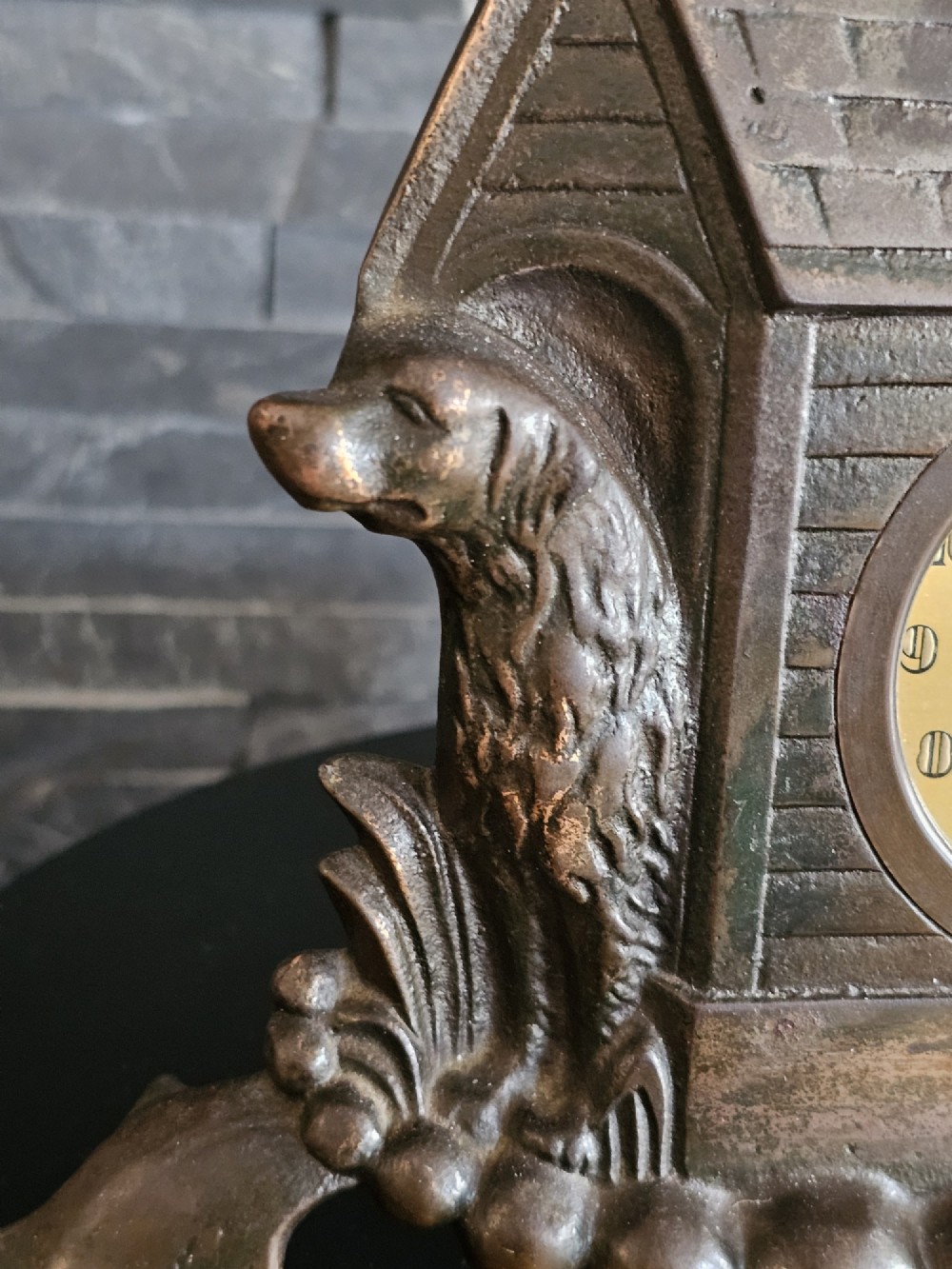 A bronzed Art Deco table clock shaped like a dog kennel with sunflowers on top and a dog figure on the left side of the circular dial. View VIII