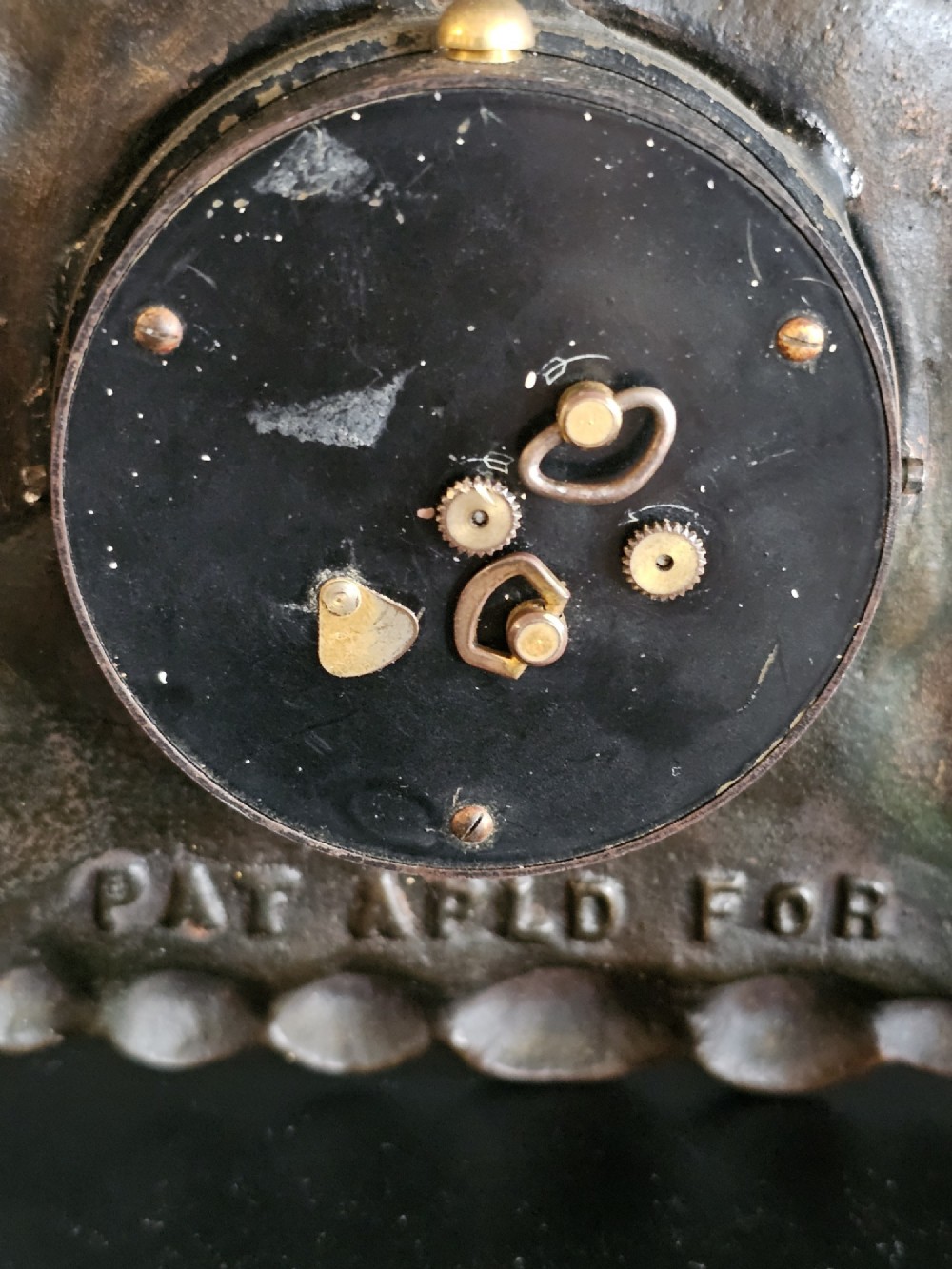 A bronzed Art Deco table clock shaped like a dog kennel with sunflowers on top and a dog figure on the left side of the circular dial. View X