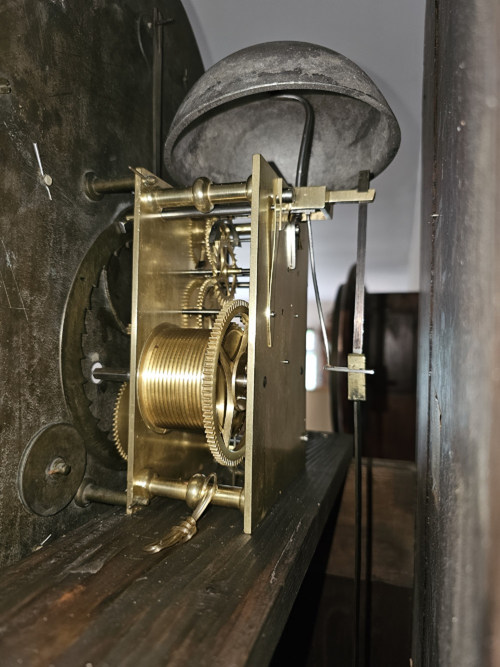 A Georgian flame mahogany longcase clock featuring an arched hood with brass-capped fluted columns, an engraved brass dial with Roman numerals, and a trunk door showcasing rich wood grain. View VII