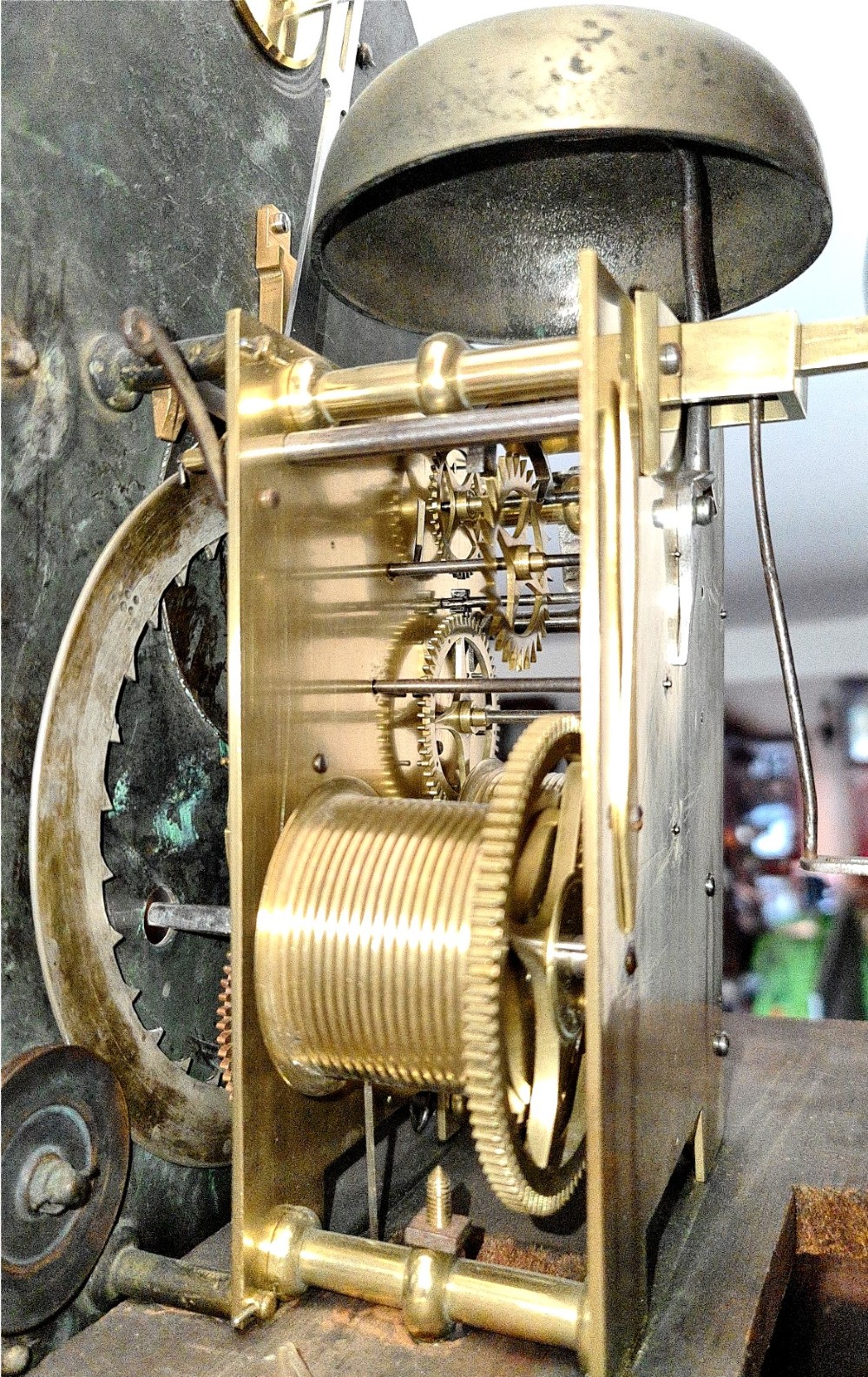 A late 18th-century Georgian mahogany longcase clock with an arched brass dial, flame mahogany trunk door, and pediment hood topped with three brass finials. View V