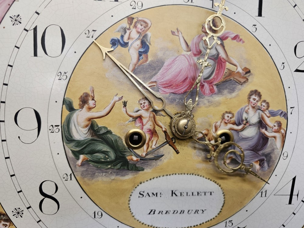 A Regency mahogany longcase clock featuring a swan-neck pediment, a painted dial with a moonphase complication, and a Gothic arch door with flame mahogany veneers. View VI