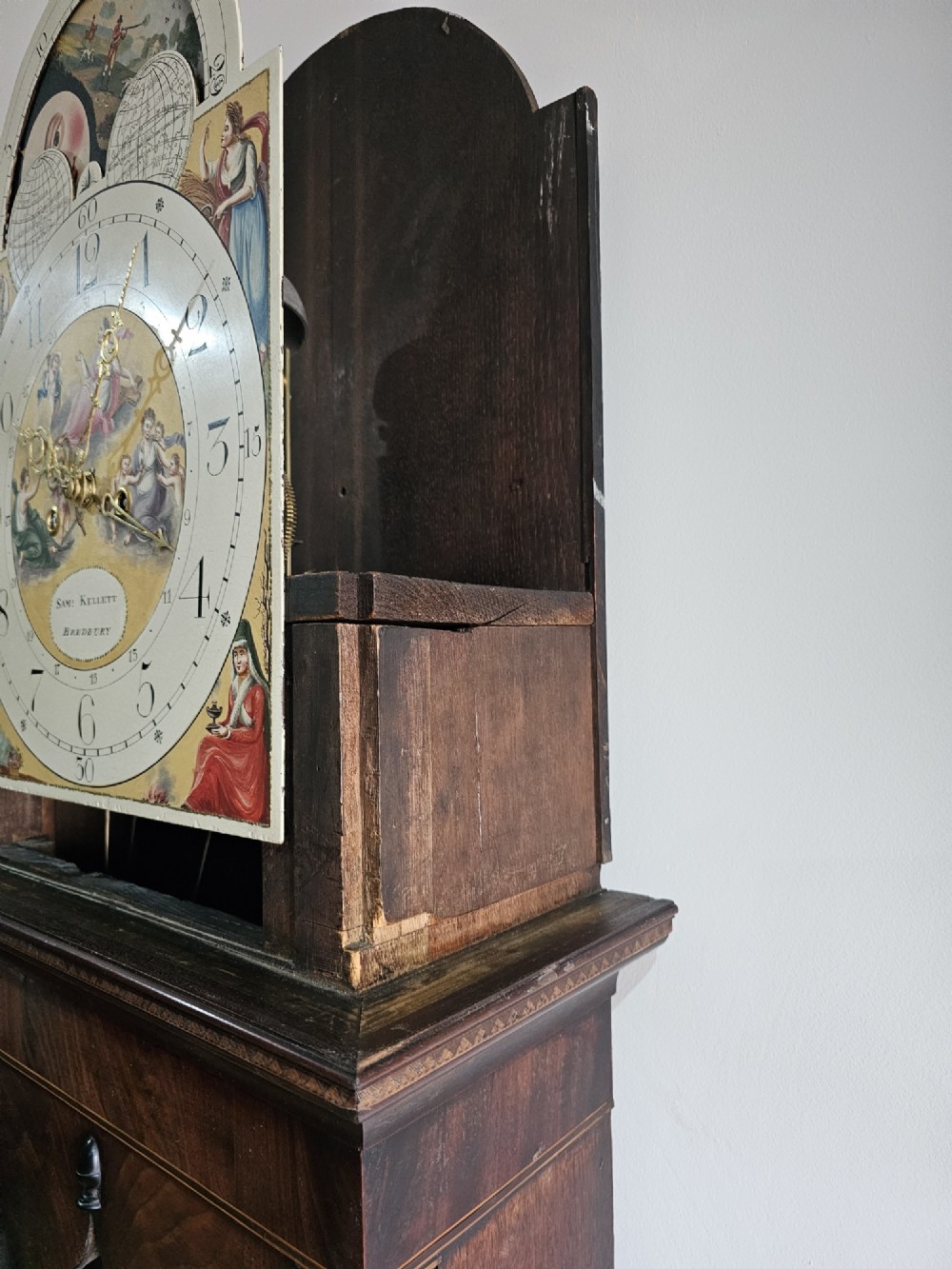 A Regency mahogany longcase clock featuring a swan-neck pediment, a painted dial with a moonphase complication, and a Gothic arch door with flame mahogany veneers. View VII
