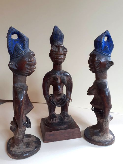 fig 2. Three hand-carved dark wood Yoruba Ere Ibeji figures featuring tall indigo-pigmented coiffures, carved facial scarification, and glass waist beads.