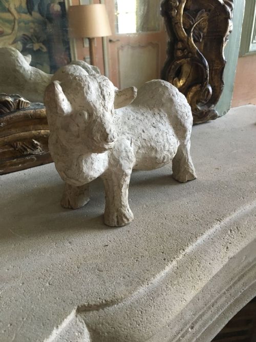 fig 1. A hand-modelled off-white terracotta sculpture depicting a stylized bull with a textured finish.