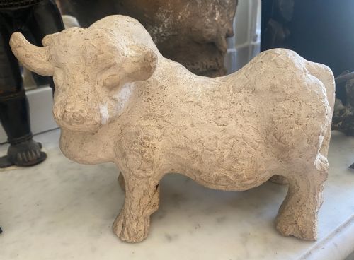 fig 2. A hand-modelled off-white terracotta sculpture depicting a stylized bull with a textured finish.