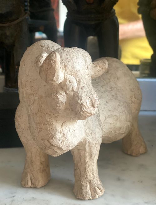 fig 3. A hand-modelled off-white terracotta sculpture depicting a stylized bull with a textured finish.