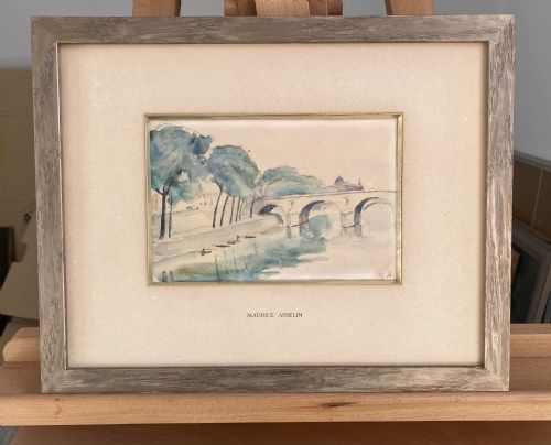 fig 4. A framed watercolour painting depicting the River Seine, trees, and the Pont Marie bridge in Paris executed in soft blue and green washes.