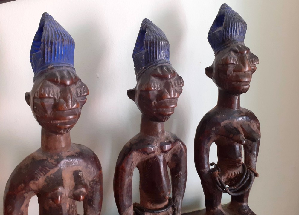 Three hand-carved dark wood Yoruba Ere Ibeji figures featuring tall indigo-pigmented coiffures, carved facial scarification, and glass waist beads. View II