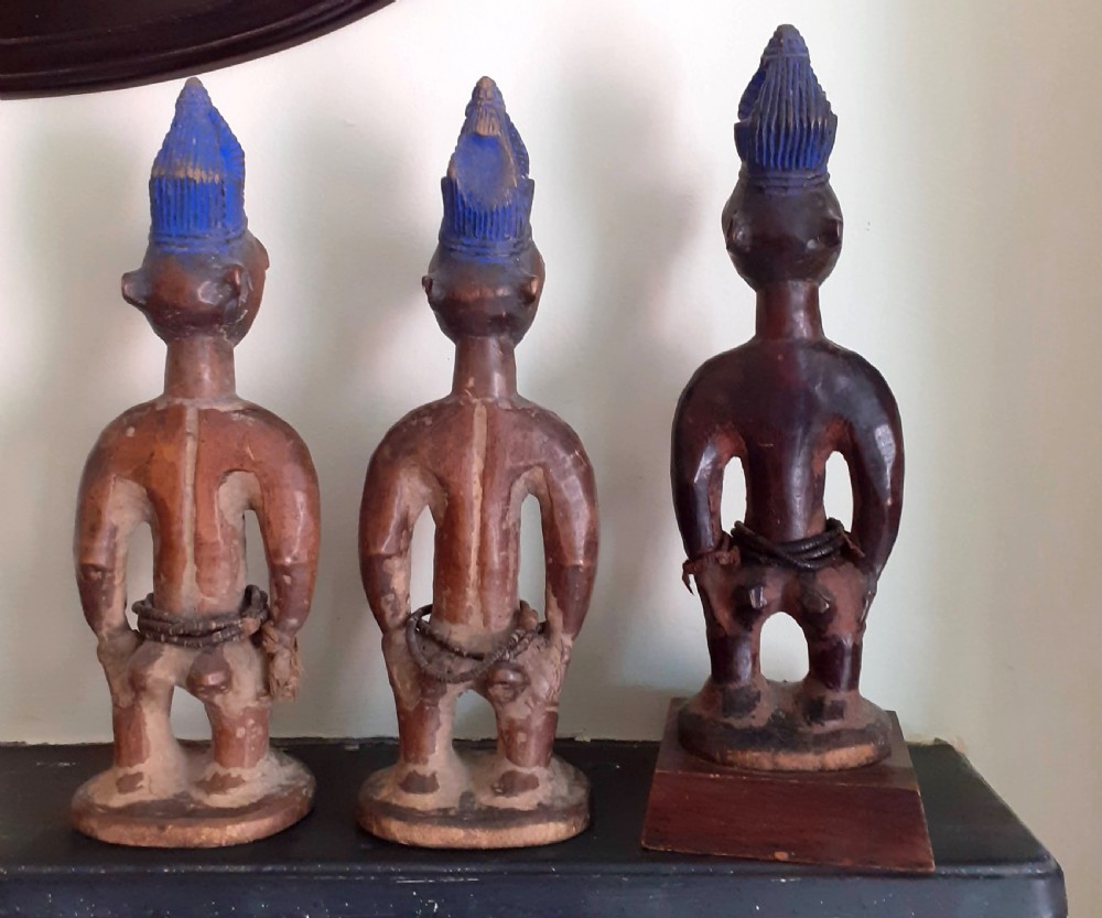 Three hand-carved dark wood Yoruba Ere Ibeji figures featuring tall indigo-pigmented coiffures, carved facial scarification, and glass waist beads. View VI