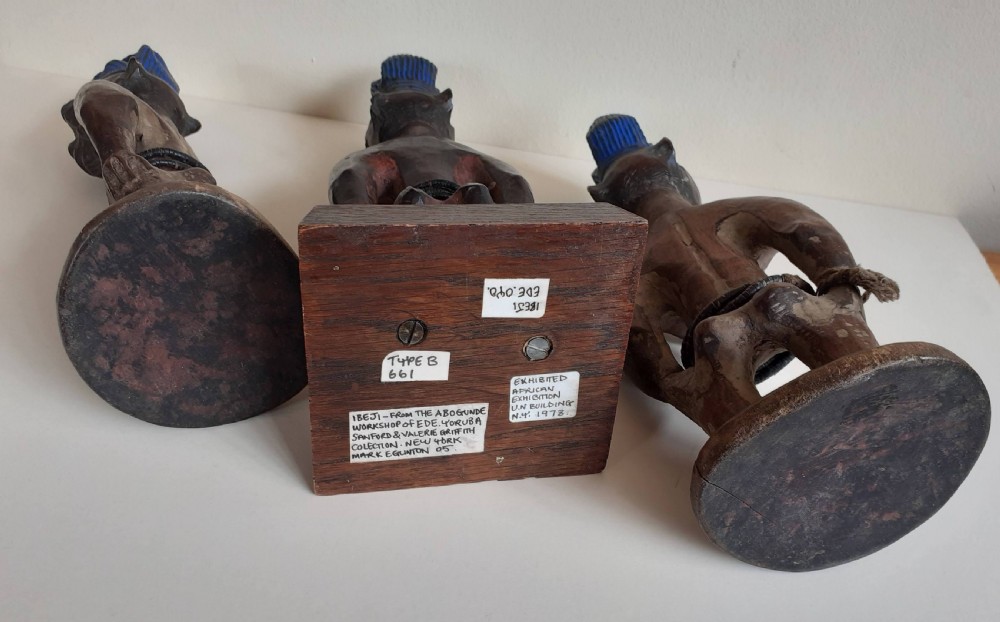 Three hand-carved dark wood Yoruba Ere Ibeji figures featuring tall indigo-pigmented coiffures, carved facial scarification, and glass waist beads. View VIII