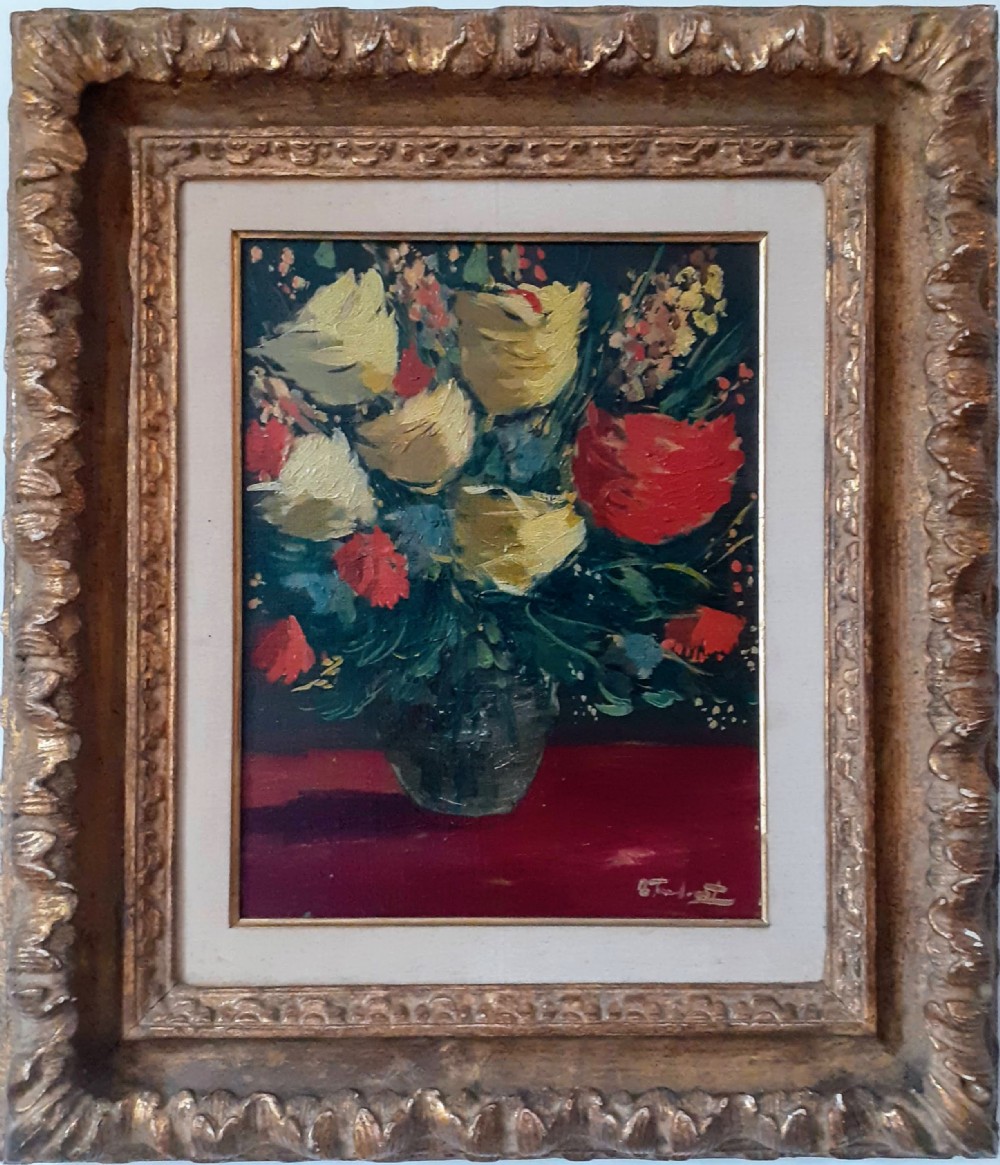 A framed oil painting on canvas depicting a bouquet of yellow and red flowers in a glass vase set on a dark red table surface.