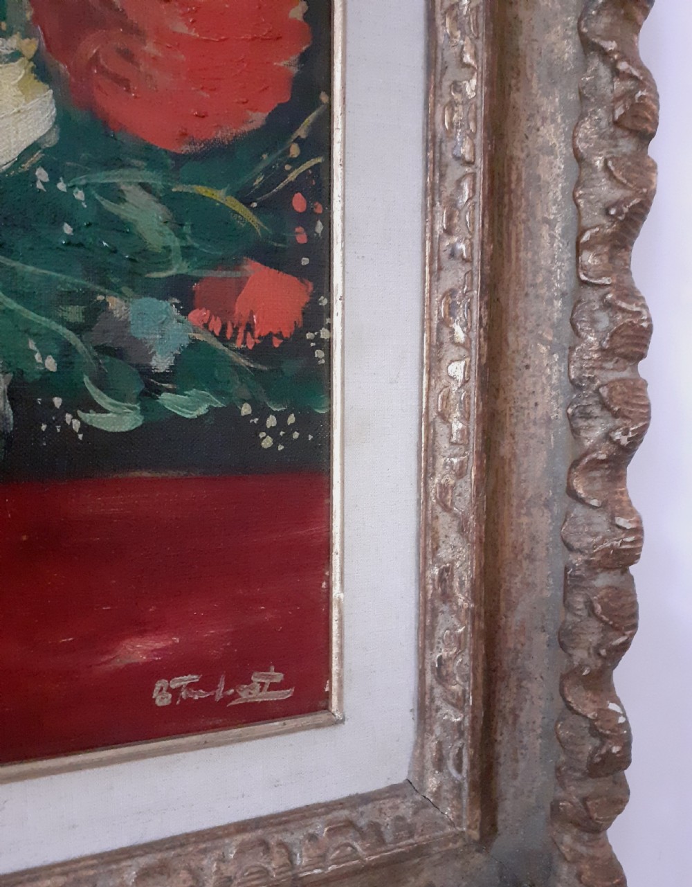A framed oil painting on canvas depicting a bouquet of yellow and red flowers in a glass vase set on a dark red table surface. View II