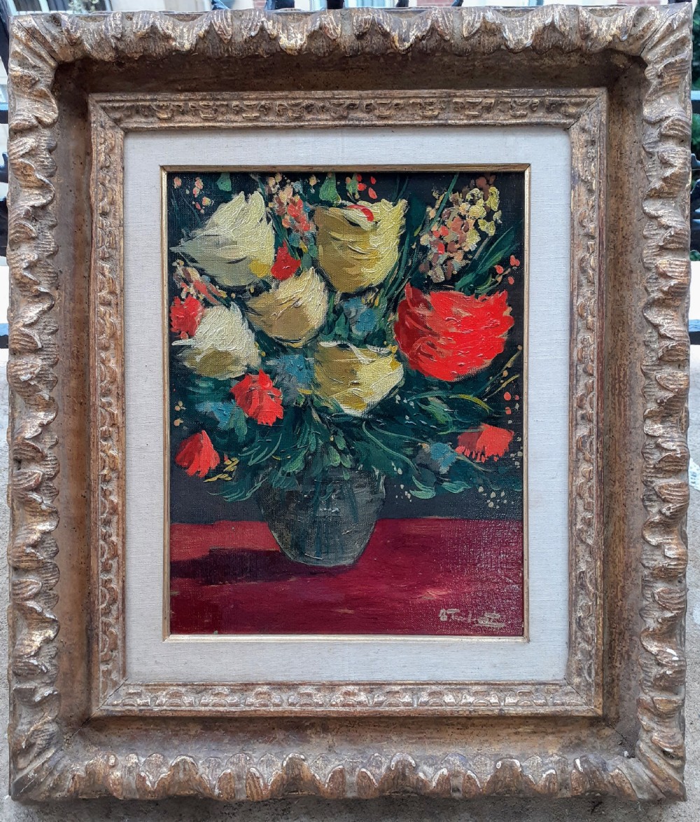 A framed oil painting on canvas depicting a bouquet of yellow and red flowers in a glass vase set on a dark red table surface. View III