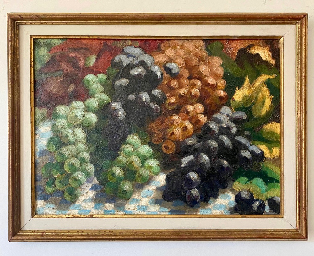 A 1930s Art Deco oil painting on canvas depicting clusters of green, black, and amber grapes resting on a blue and white chequered tablecloth. View V