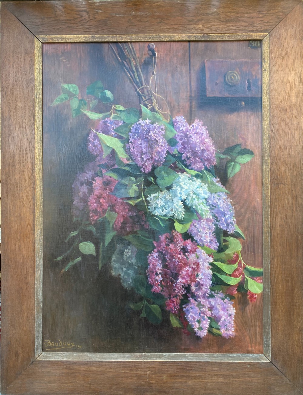 An oil on canvas painting dated 1901 depicting a bouquet of purple and white lilac flowers hanging against a dark oak wooden door. View III