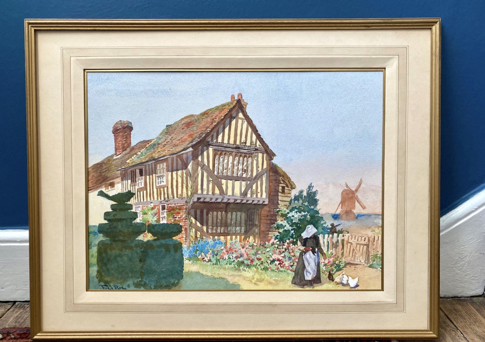 An Edwardian watercolour painting depicting a half-timbered coastal cottage with shaped topiary, a figure feeding chickens in a flower garden, and a distant windmill. View III