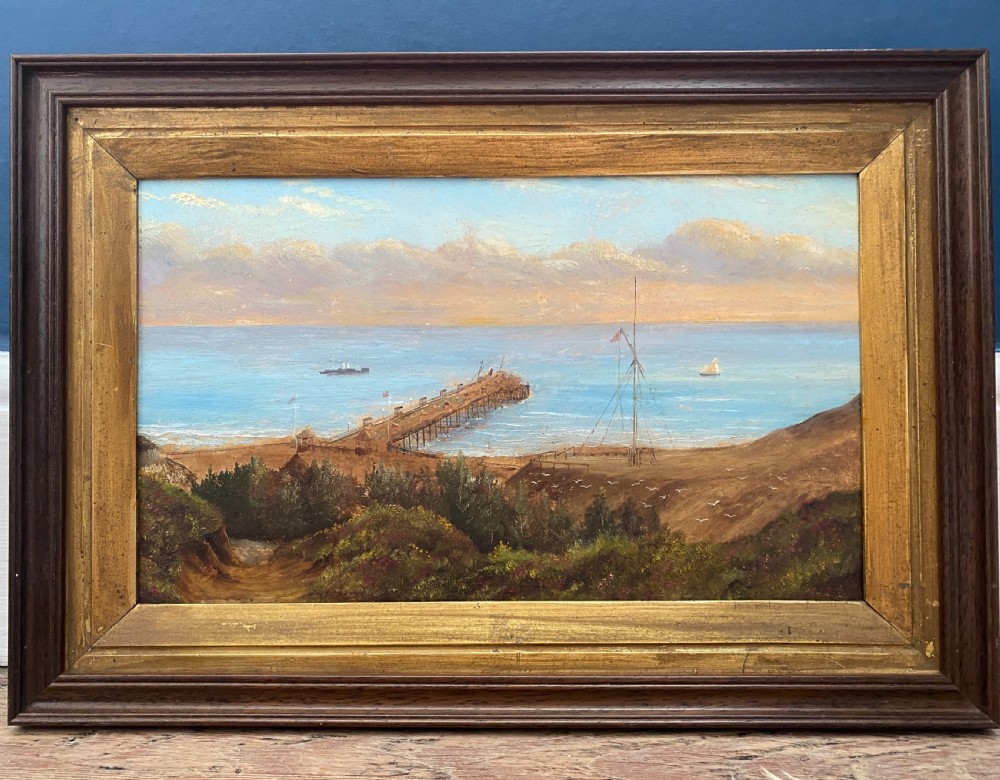 Victorian topographical oil painting on board depicting Boscombe Pier in Dorset with steamships on blue water and coastal cliffs in the foreground. View V
