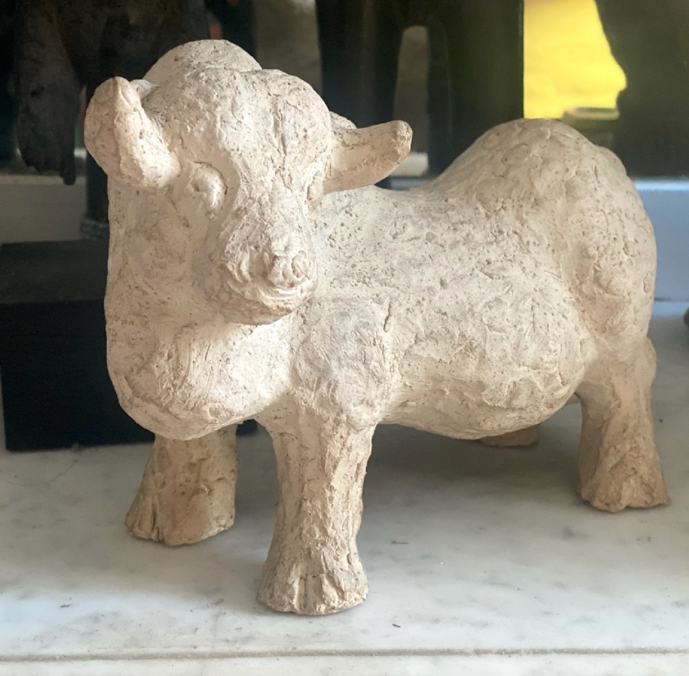 A hand-modelled off-white terracotta sculpture depicting a stylized bull with a textured finish.