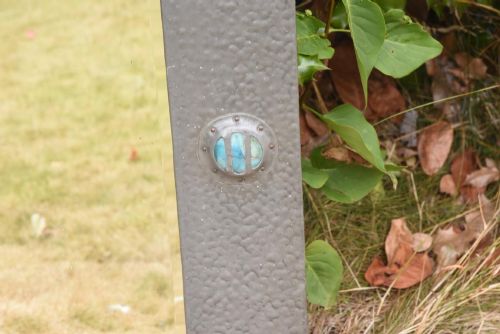fig 2. A rectangular Arts and Crafts wall mirror featuring a hammered pewter metal frame decorated with corner rivets and two circular turquoise ceramic cabochons on the side borders.
