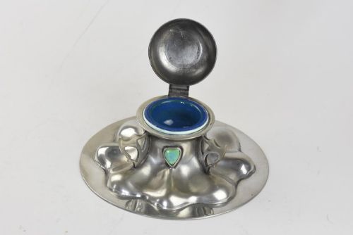 fig 1. A polished pewter Arts and Crafts inkwell featuring a flared lobed base, stylized handles, and two inset turquoise ceramic cabochons.