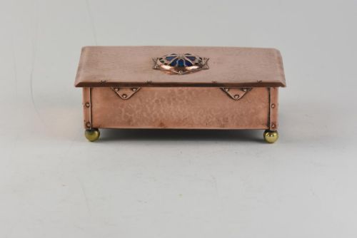 fig 2. A rectangular hand-hammered copper box featuring brass ball feet, riveted corners, and a central blue enamel cabochon with a pierced butterfly overlay on the lid.